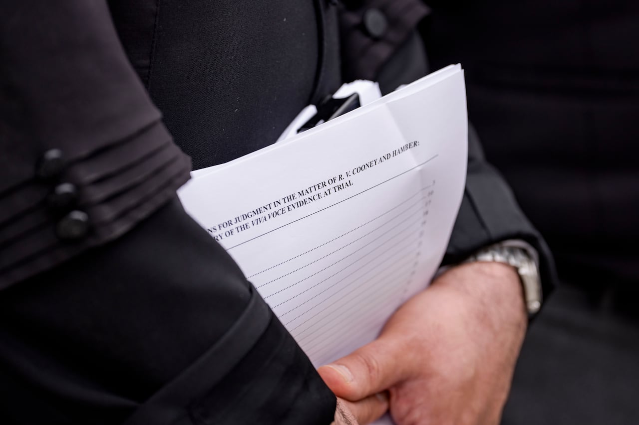 Close up of a person wearing black holding a handful of papers.