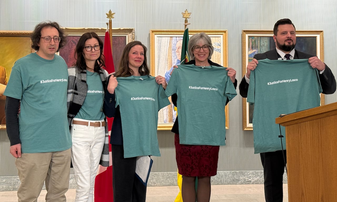 A group of five people wearing or holding green shirts with the phrase "#JusticeforHenryLosco" on them.