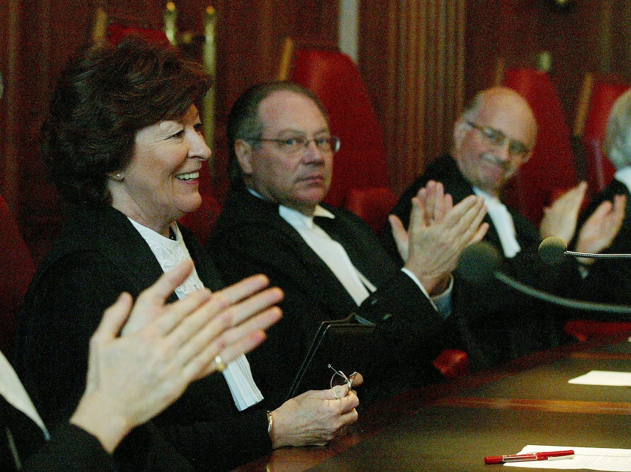 Arbour sits on the Supreme Court bench flanked by other justices as they clap and applaud her time with them.
