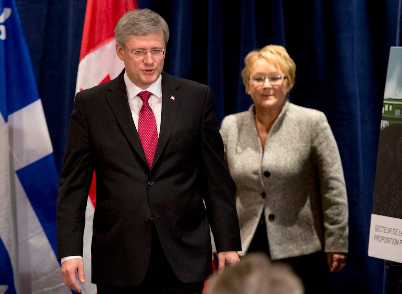 Two people in business attire enter a news conference room.