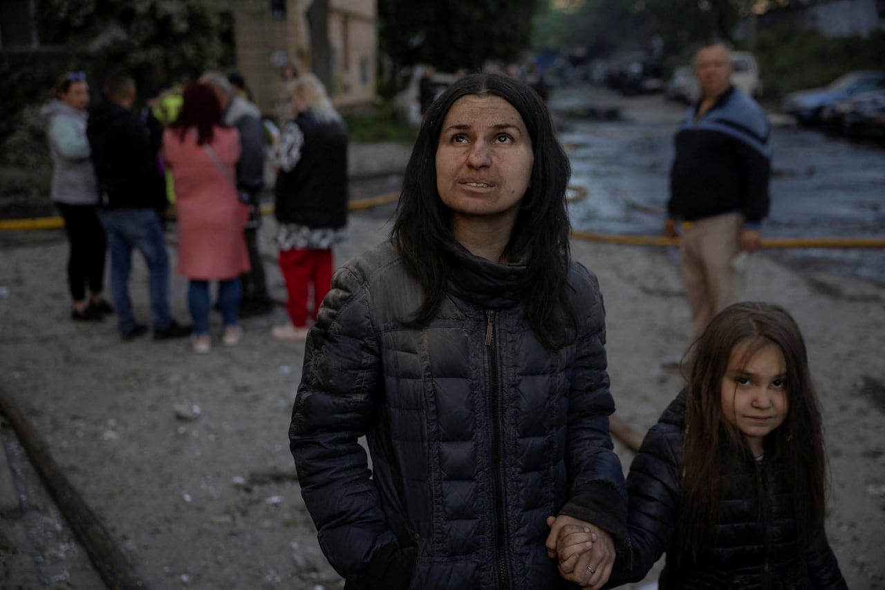 A woman and a young girl walk among debris from a missile and drone attack
