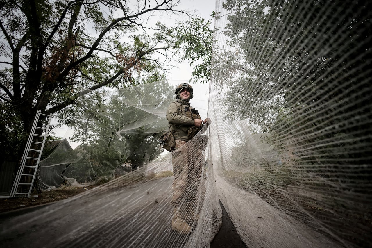 A Ukrainian soldier is seen installing anti-drone netting in Kostiantynivka, in Ukraine's Donetsk region.