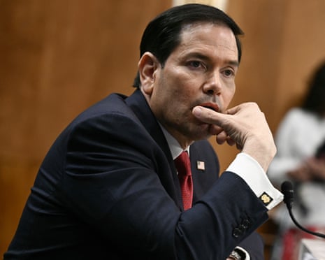 Secretary of State Marco Rubio rests his chin on his hand while sitting at a hearing