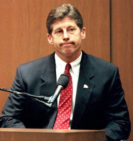 Detective Mark Fuhrman in a dark suit and red polka-dot tie sits at a witness stand with a microphone