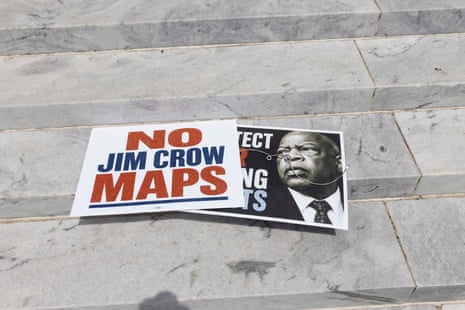 Protest signs reading 'NO JIM CROW MAPS' lie on Alabama state capitol steps with a photo of a person
